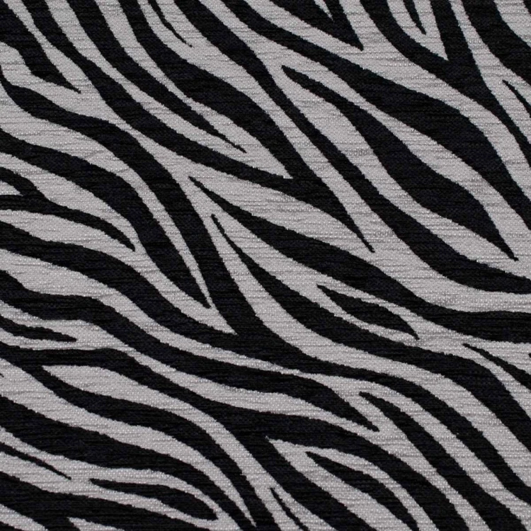 Zebra szaro-czarna. Zbliżenie na materiał tapicerski o grubym splocie, przedstawiający organiczny, zwierzęcy wzór zebry. Kolorystyka to ciemna, nasycona szarość i głęboka czerń, co nadaje tkaninie nowoczesny i drapieżny charakter.